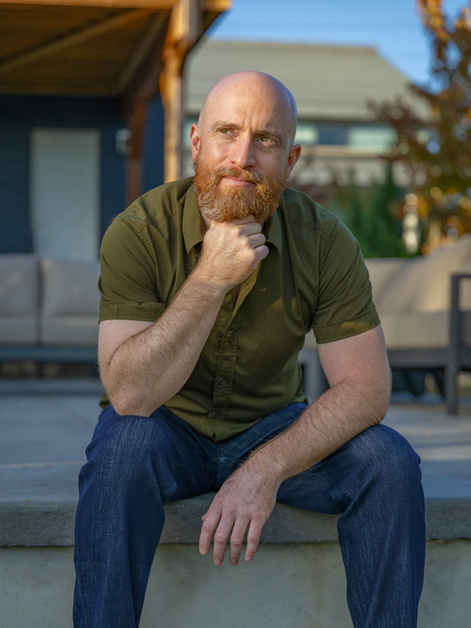Charles Edward Pax seated outdoors in an olive-green shirt, resting his chin on his hand